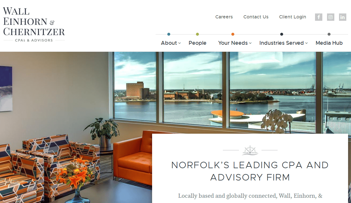 A modern office lounge with colorful chairs and a coffee table overlooks a waterfront cityscape through large windows. Text reads Wall Einhorn & Chernitzer: Norfolk’s leading CPA and advisory firm.