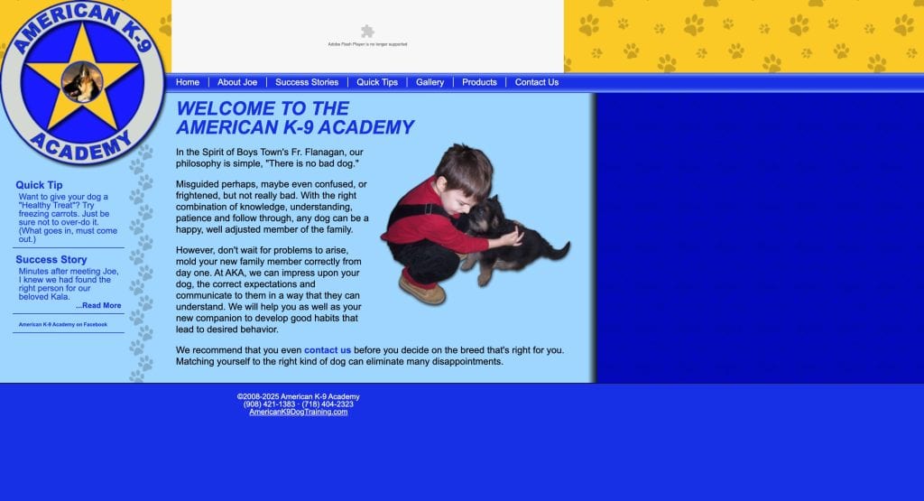Screenshot of American K-9 Academy website showing a boy in red and black kneeling on blue carpet, hugging a black puppy. The left sidebar has navigation links and a dog paw print banner is at the top.