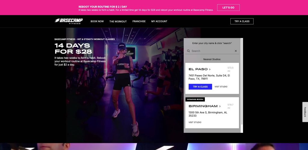 A fitness instructor leads a workout class on stage, with participants exercising in a dimly lit studio. A promo banner offers 14 Days for $28. A search bar and studio list appear on the right side of the screen.
