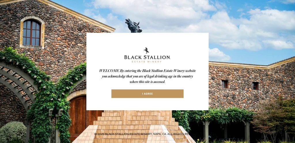 A stone winery building with arched doors and windows, green vines climbing the walls, and a statue of a horse overhead. A welcome pop-up for Black Stallion Estate Winery appears in the center.