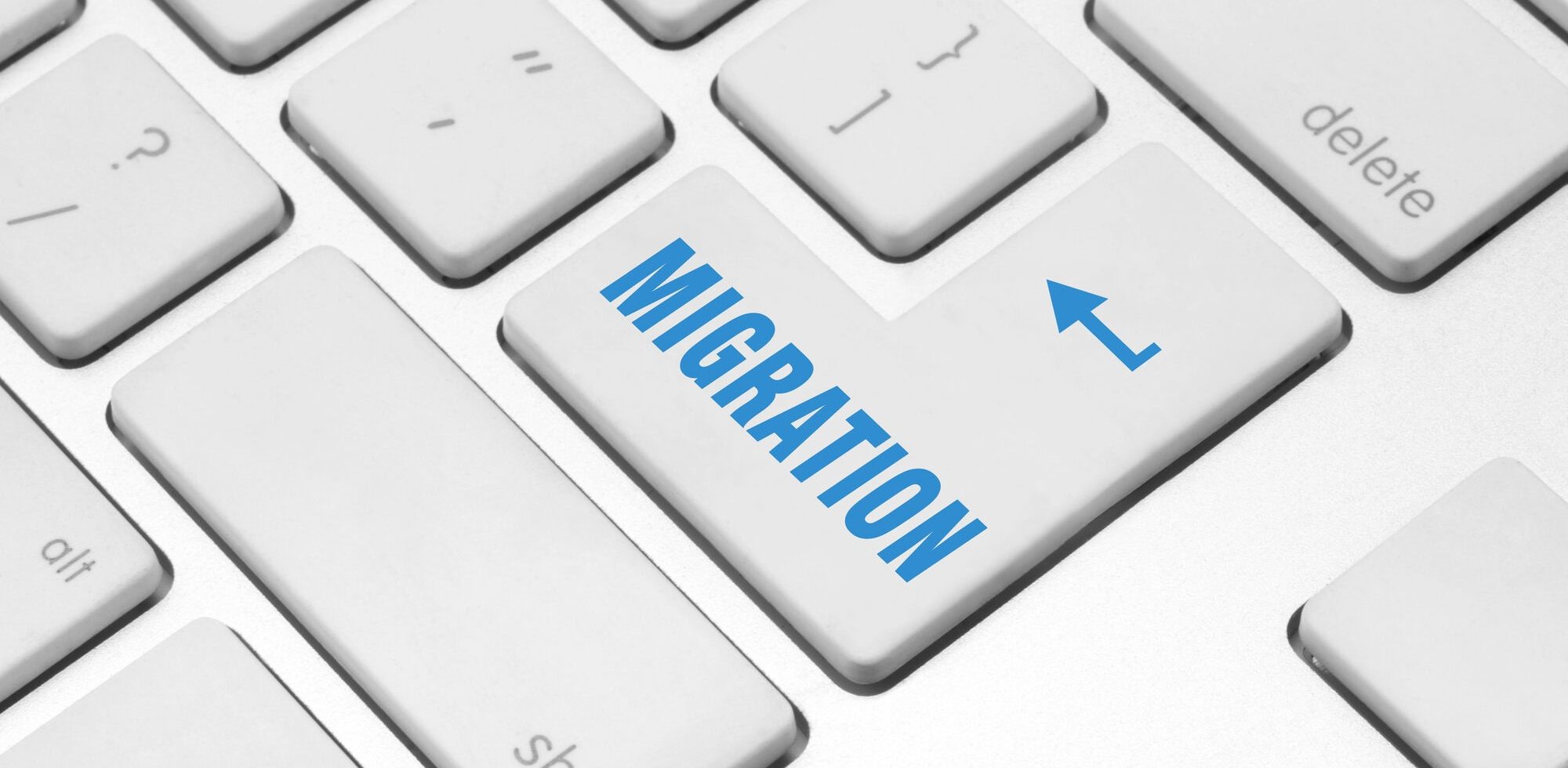 A white computer keyboard with a large Enter key labeled MIGRATION in blue text and an arrow, symbolizing the concept of WordPress Migration or upgrading from an outdated migration process.