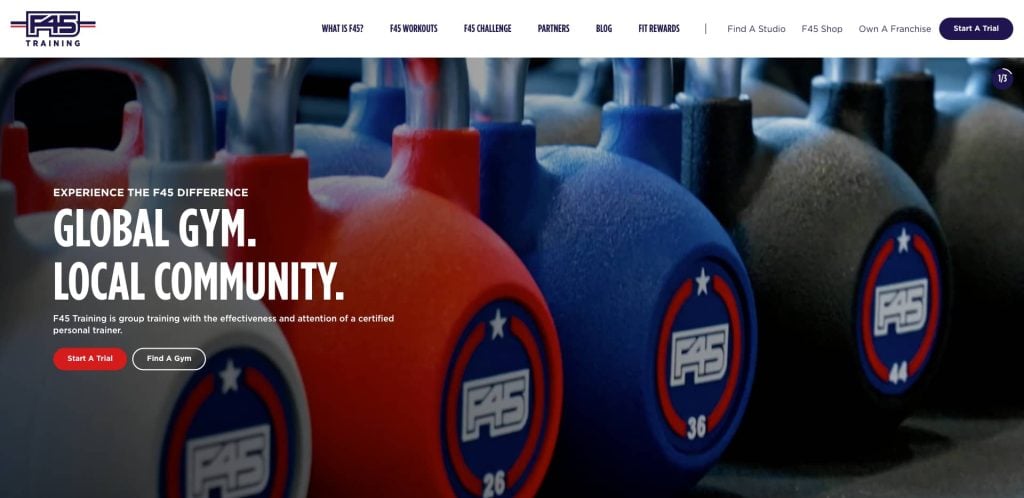 A row of colorful F45-branded kettlebells, with white bold text overlay reading GLOBAL GYM. LOCAL COMMUNITY. promoting F45 Trainings group workout programs.