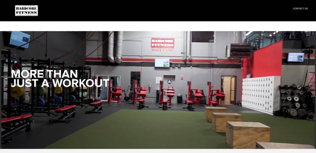 A gym interior with red and black exercise equipment, wooden plyo boxes, weightlifting platforms, and lockers. A sign on the wall reads Hardcore Fitness. Text overlay says, More than just a workout.