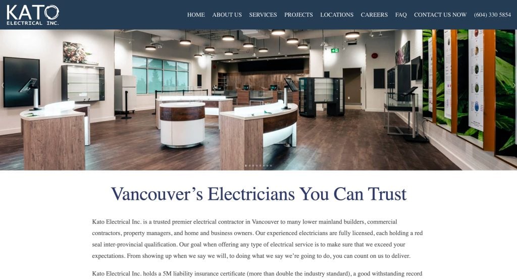 Spacious, modern electrical showroom with wooden floors, white display islands, high ceilings, and various lighting fixtures; Kato Electrical branding and website navigation at the top.