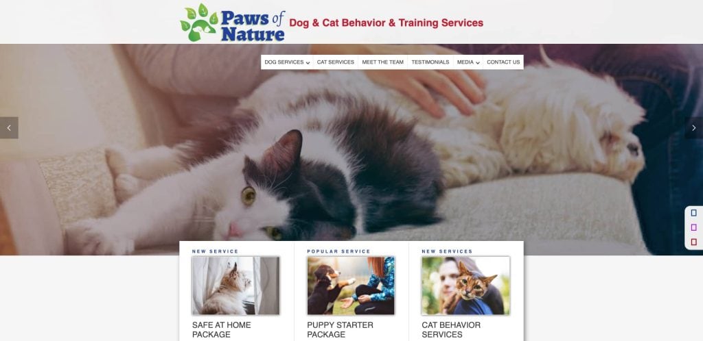 A person pets a relaxed black and white cat lying near a golden retriever. The website banner reads Paws of Nature: Dog & Cat Behavior & Training Services with service options and images below.