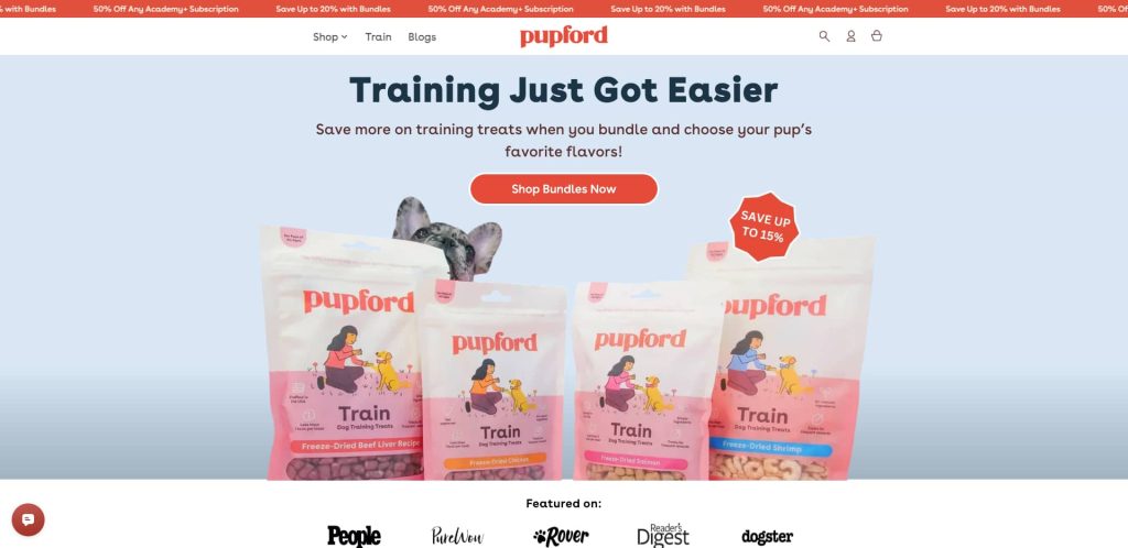 A website banner for Pupford featuring dog training treats in pink and white bags, a dog peeking from behind the products, and a call-to-action button that reads Shop Bundles Now.