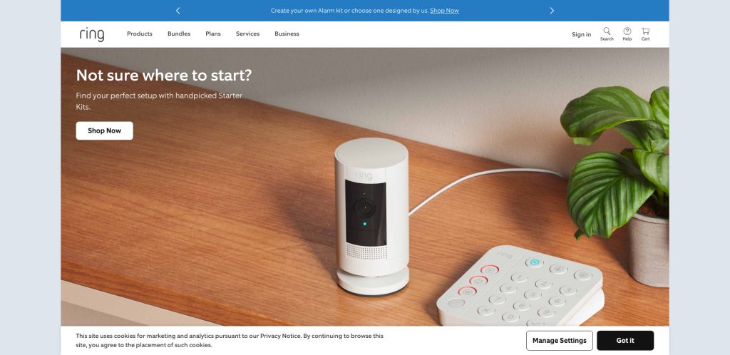 A Ring security camera sits on a wooden surface next to a white security keypad and a small green potted plant. A Stop Now button is visible, with text encouraging users to find starter kits.