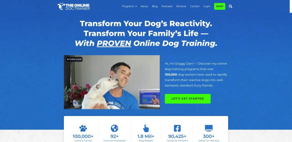 A man wearing a blue T-shirt sits smiling and holding a white dog that licks his face, with website text promoting proven online dog training, a green Lets Get Started button, and dog training statistics below.