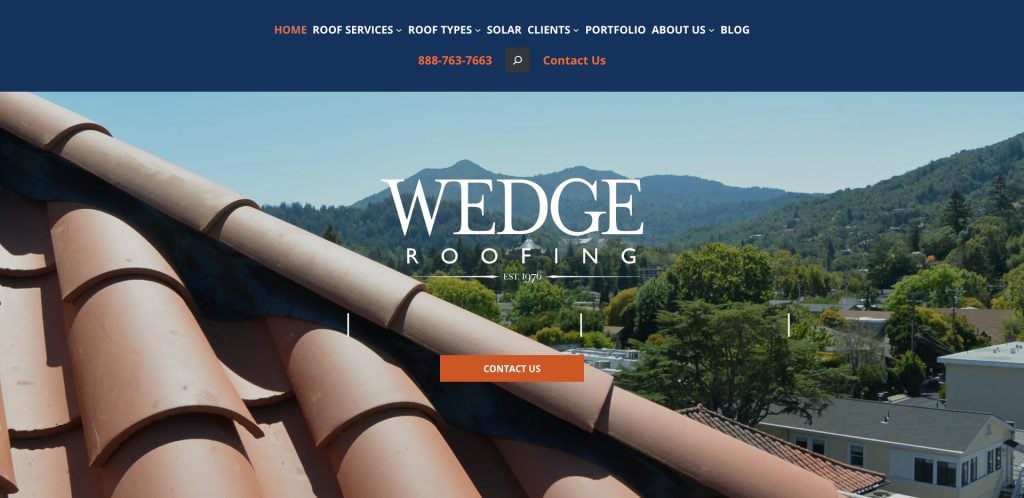 View of roof tiles with trees and mountains in the background. The website header displays navigation links for home, services, and contact information for Wedge Roofing. A Contact Us button is centered on the image.