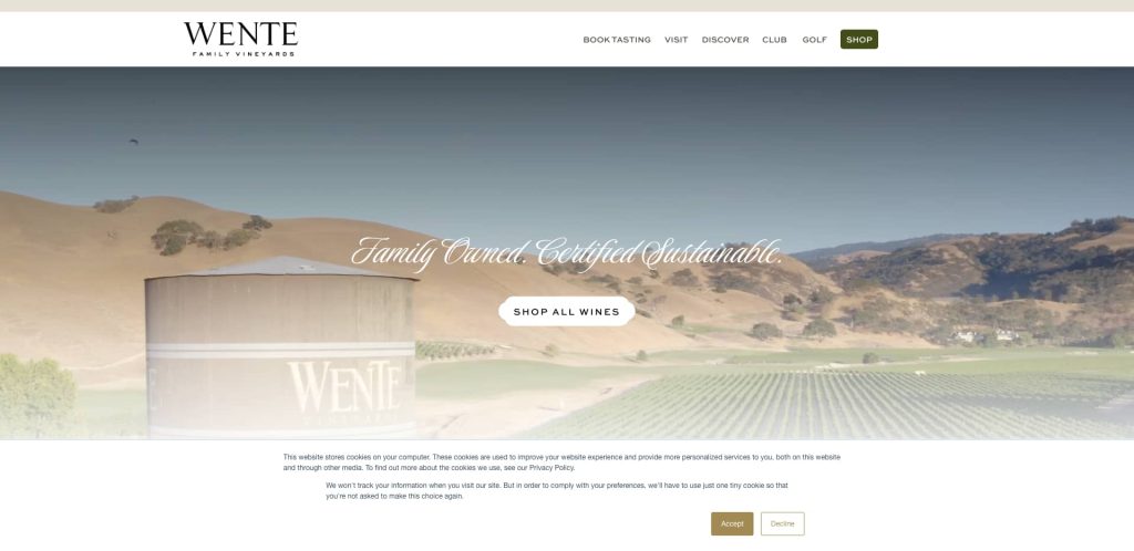 A vineyard landscape with rolling hills and a large water tank labeled Wente. Text reads Family Owned. Certified Sustainable. with buttons for shopping wines and cookie consent at the bottom.