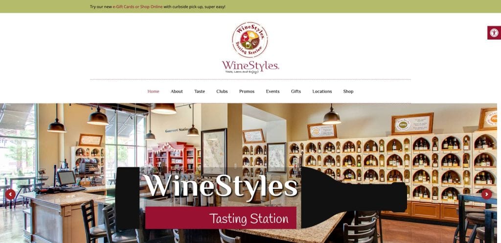 Screenshot of the WineStyles Tasting Station website homepage, showing a wine shop interior with shelves of wine bottles, a checkout counter, and navigation menu options at the top.