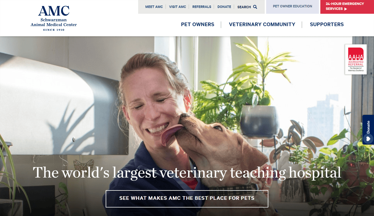 A smiling woman in a blue jacket is nuzzled by a happy brown dog. The image, featured on the professional veterinary website of AMC Animal Medical Center, includes the text: The world’s largest veterinary teaching hospital.