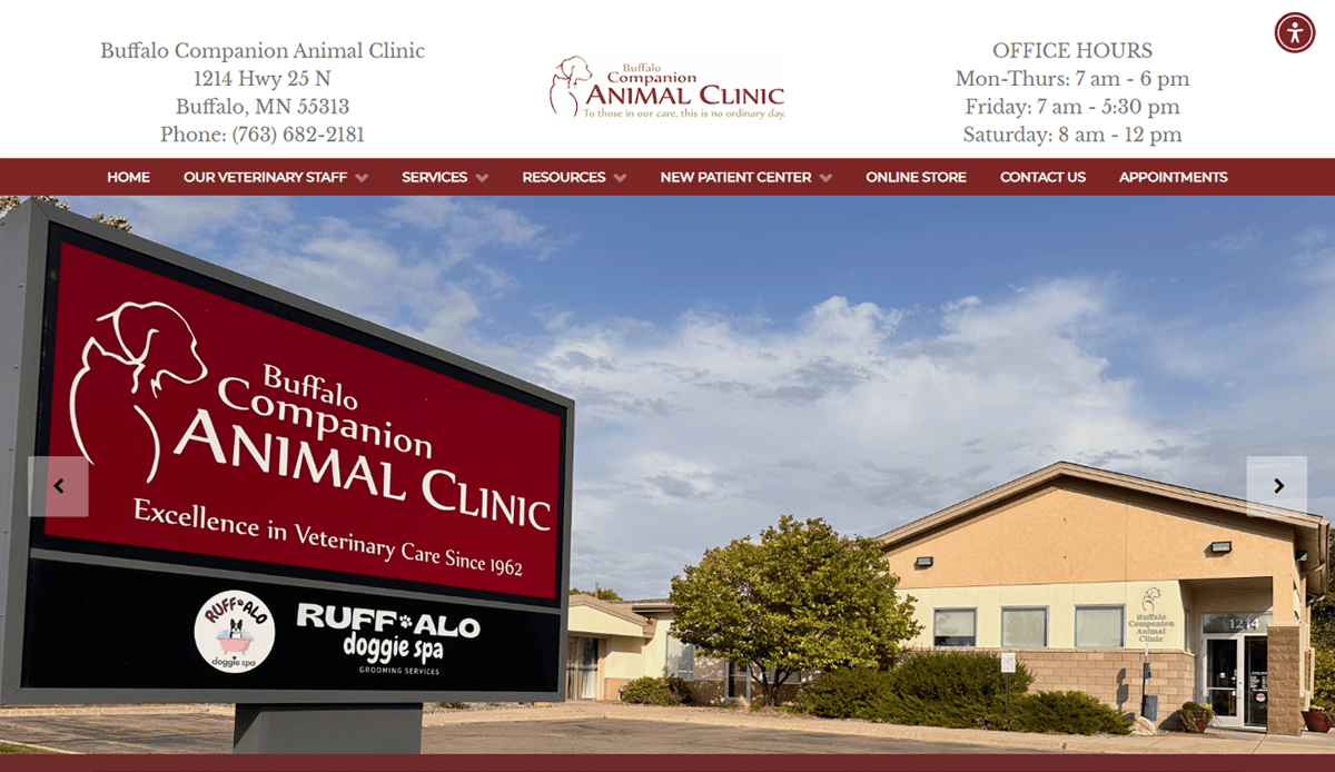 Exterior view of Buffalo Companion Animal Clinic with a large sign in front displaying the clinic’s name and a dog graphic—perfect inspiration for professional veterinary website design; building and parking lot visible under a partly cloudy sky.