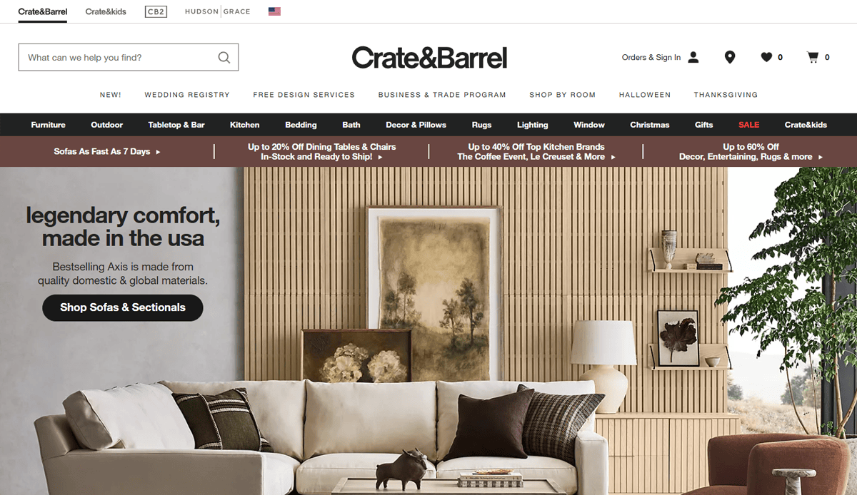 Crate & Barrel’s Furniture Website Design homepage showcases a modern living room with a white sectional sofa, beige walls with vertical wood slats, styled shelves, and framed artwork above the sofa.