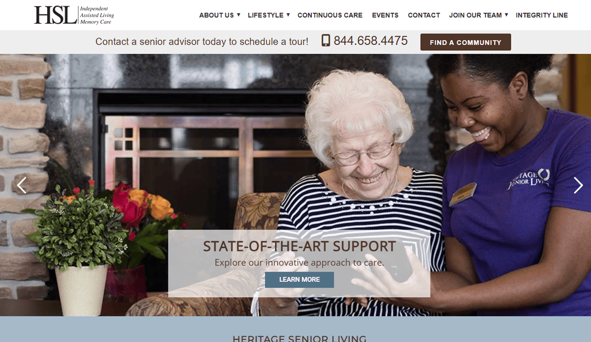 A smiling caregiver in a purple shirt helps an elderly woman with white hair and glasses, both looking at a tablet in a cozy room. “State-of-the-Art Support.” Highlighting Assisted Living Website Design for modern care communities.