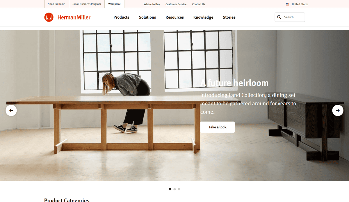 A woman leans over a long wooden dining table in a modern, light-filled room. Text reads: A future heirloom. Discover Land Collection—a dining set crafted for years of gathering, perfect for any furniture website design vision.