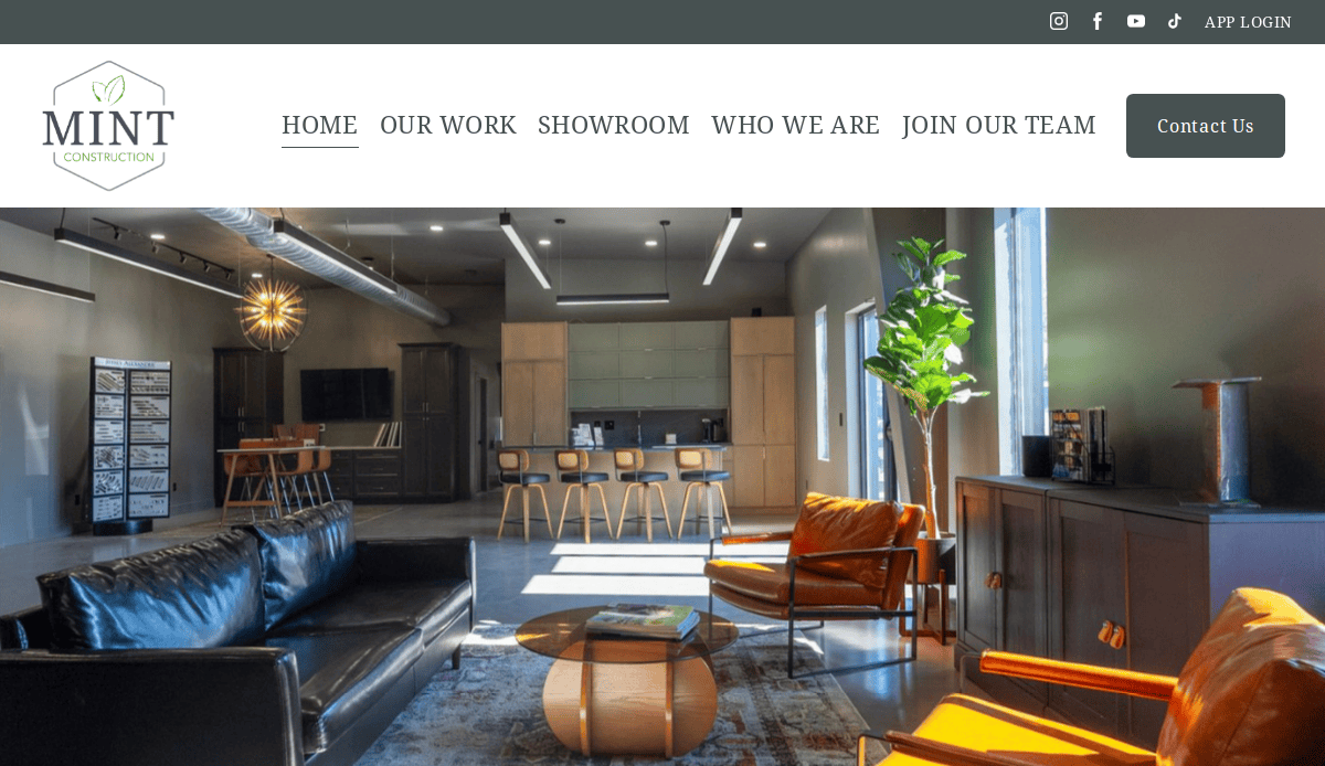 A modern office lobby with leather sofas, armchairs, a coffee table, large windows letting in sunlight, and plants. The sleek website design features navigation links at the top alongside the Mint Construction logo to help convert visitors.