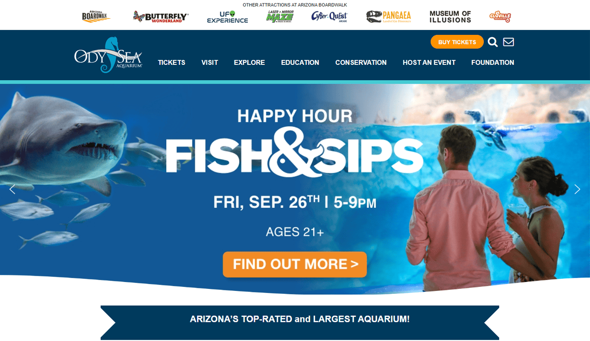 A man and woman stand in front of a large aquarium display with sharks swimming; text promotes Fish & Sips happy hour at OdySea Aquarium on Friday, Sept. 26th, 5–9pm, captivating visitors ages 21 and over.
