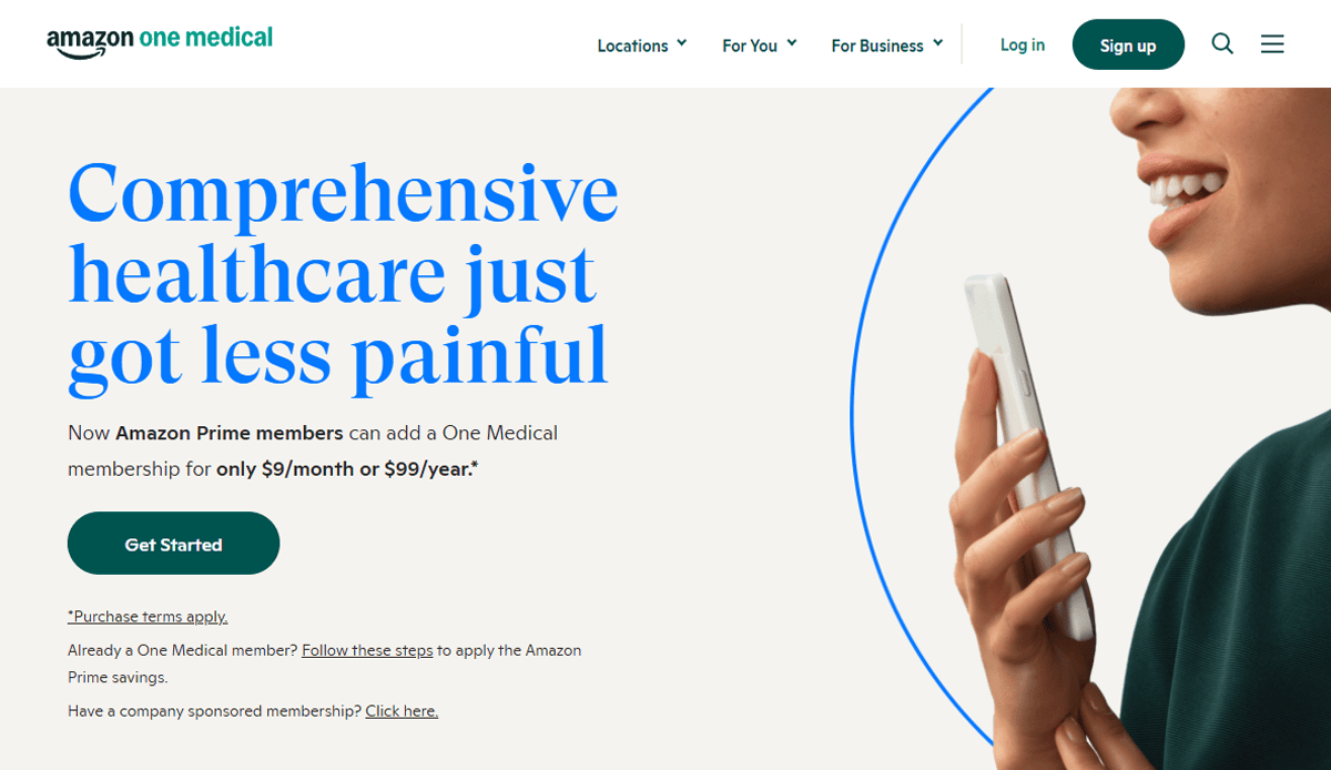 A woman holding a smartphone smiles on the right. On the left, bold blue text reads, “Comprehensive healthcare just got less painful.” Buttons and smaller text highlight health & wellness benefits of Amazon One Medical membership. Amazon One Medical logo is at the top.