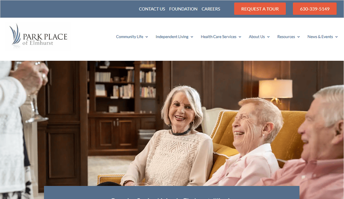 Three older adults sit together on a yellow couch, smiling and laughing in a warmly lit living room—a perfect scene for an Assisted Living Website, capturing the warmth and community residents can experience.