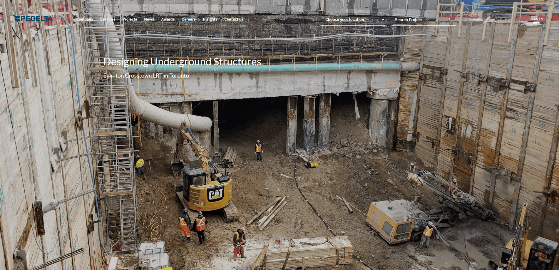 A construction site shows workers, machinery, and equipment inside a deep excavation surrounded by wooden retaining walls, illustrating a practical civil engineering guide with large pipes and ladders leading in and out of the pit.