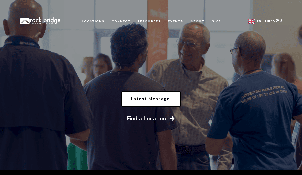 A group of people stand together indoors, smiling and talking. The screen displays options: Latest Message and Find a Location, highlighting how a church website design serves as a vital ministry tool. The Rock Bridge logo and website menu are visible at the top.