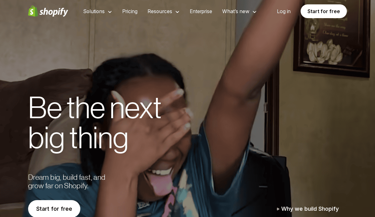 A person smiling excitedly and raising one arm while covering part of their face, with "Be the next big thing," Shopifys navigation menu, and a hint of B2B website design inspiration overlaid on the image.