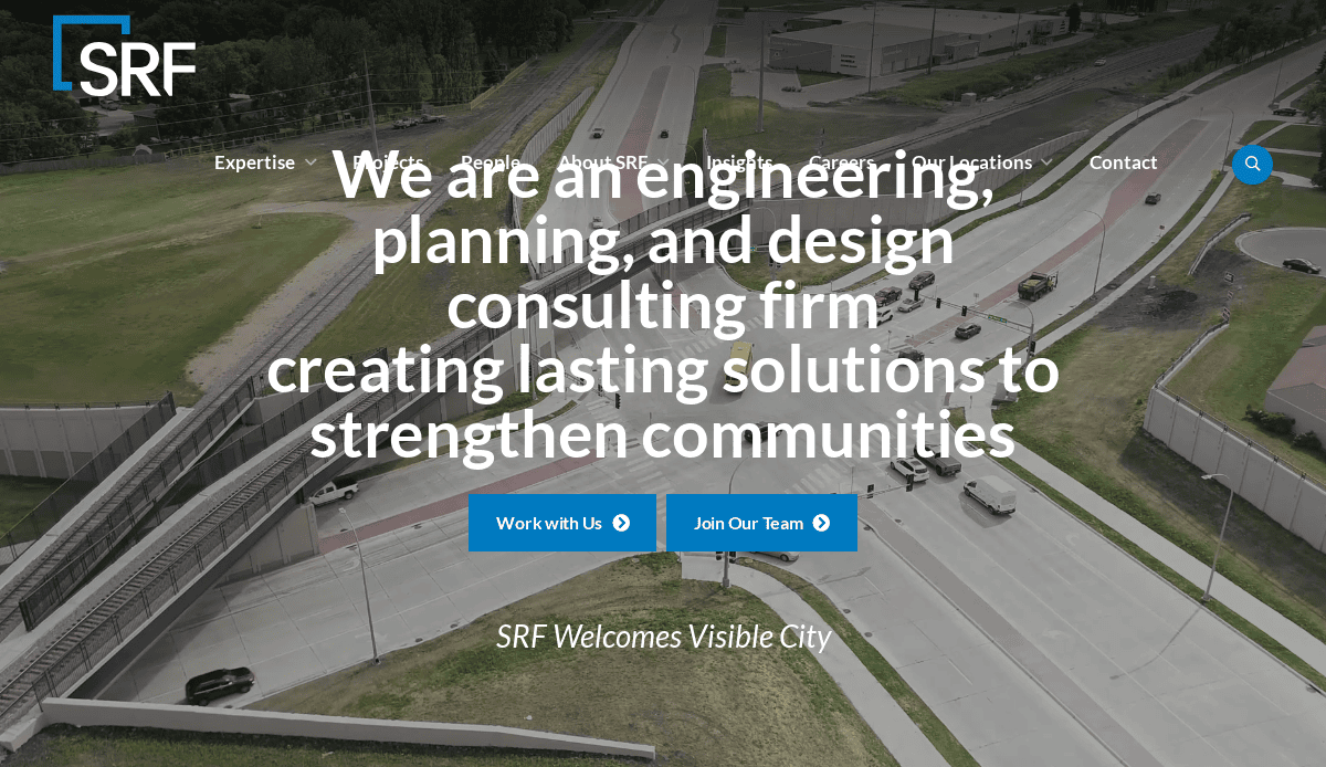 Aerial view of a busy highway interchange with multiple lanes and cars; large white text highlights SRF as a civil engineering, planning, and design consulting firm. Two blue buttons—“Work with Us” and “Join Our Team”—guide visitors through the website.