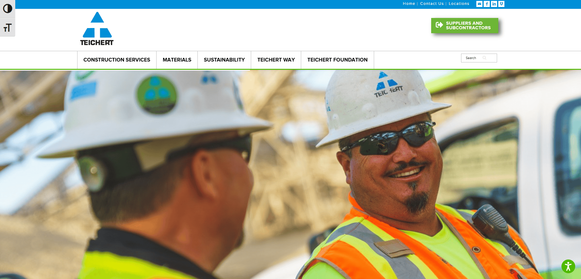 Two construction workers in safety gear and helmets smile and talk at a job site. A white truck, construction equipment, and an asphalt contractor guide are visible in the background.