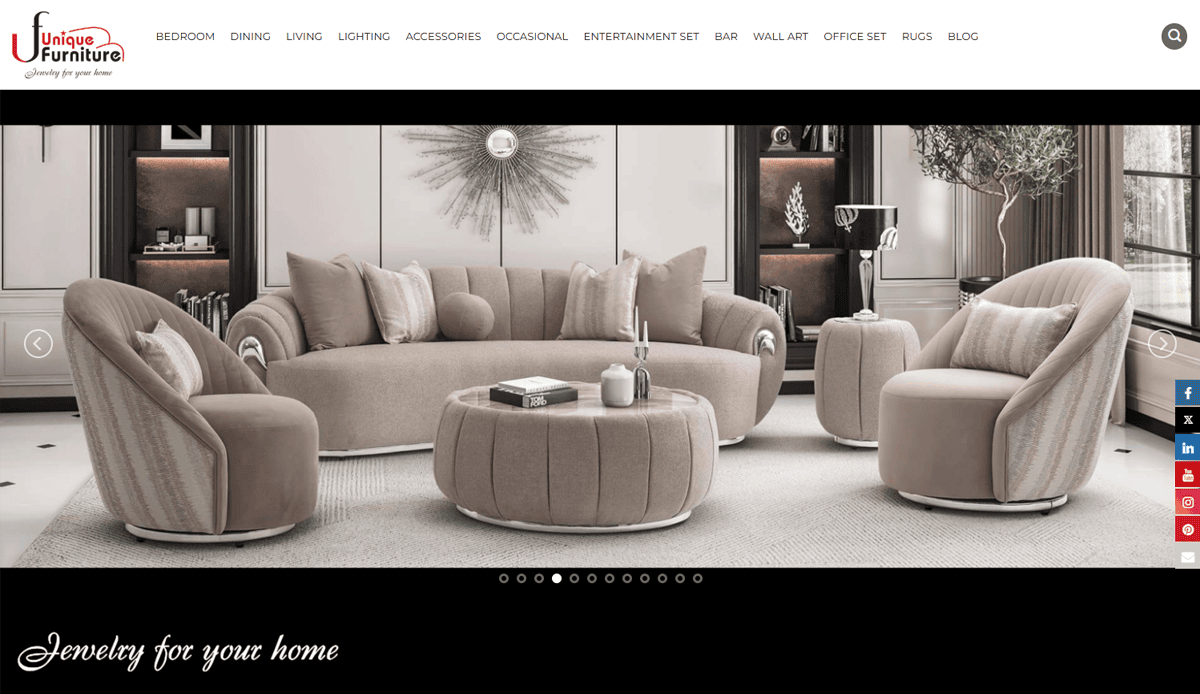 A modern living room set with a beige sofa, two armchairs, and a round coffee table sits on a light rug. Decorative items and vases are displayed in the background—ideal inspiration for furniture website design.
