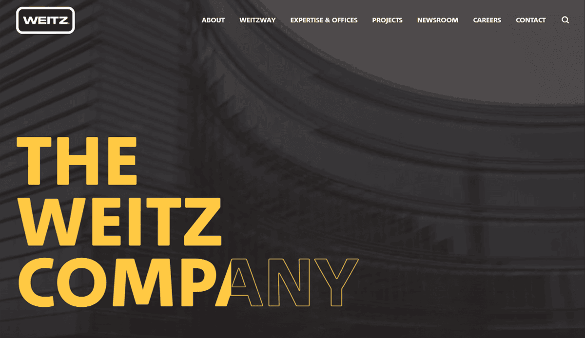Website homepage for The Weitz Company, featuring a modern building background and large yellow text reading THE WEITZ COMPANY, showcasing professional commercial construction expertise with a sleek navigation menu at the top.