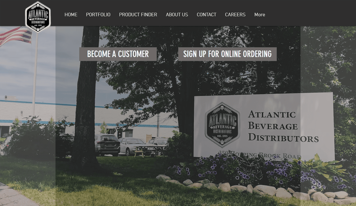 Front view of Atlantic Beverage Distributors building with a sign, lush landscaping, and parked cars; highlights user engagement through intuitive beverage distributor website design with clear “Become a Customer” and “Sign Up for Online Ordering” buttons.