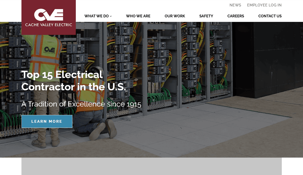 Two workers in safety vests and hard hats kneel by open electrical panels with many wires. Overlay text reads Top 15 Electrical Contractor in the U.S. Commercial Electrician Excellence Since 1915. Cache Valley Electric logo is above.