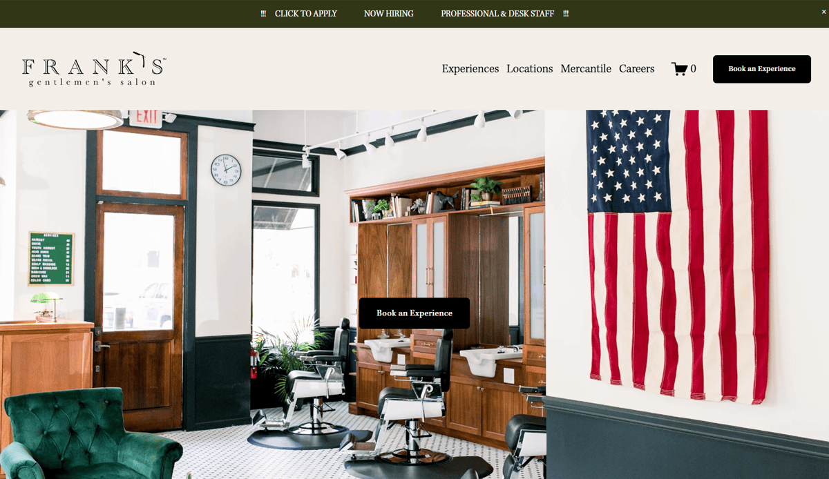 A stylish barbershop interior with vintage chairs, large mirrors, and a U.S. flag on the wall—perfect inspiration for any barber shop website design. Bright natural light highlights dark wood accents and crisp white walls.
