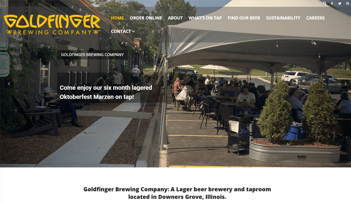 Screenshot of Goldfinger Brewing Company’s website showing outdoor seating under a tent with people enjoying drinks. The brewery website features their six-month lagered Oktoberfest Marzen on tap and easy navigation options.