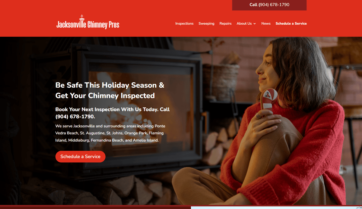 A woman in a cozy room sits by a fireplace, holding a red mug and smiling. The screen shows Jacksonville Chimney Pros’ chimney repair website design, highlighting conversion features like the bright red Schedule a Service button for easy booking.