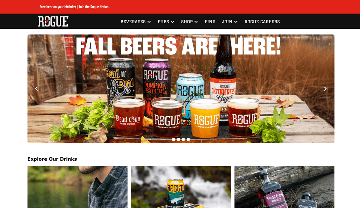 A website homepage for Rogue featuring a banner with the text FALL BEERS ARE HERE! above various Rogue beer bottles, cans, and glasses outdoors on a wooden surface with greenery, showcasing brewery website design and future-ready features.
