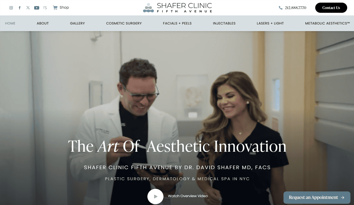 A man in a white medical coat and a woman in black scrubs smile while walking inside a modern clinic, showcasing cosmetic surgery website design elements like the Shafer Clinic Fifth Avenue header—perfect for building trust with potential patients.